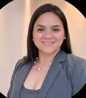 Retrato profesional de una mujer con blazer gris y collar de perlas